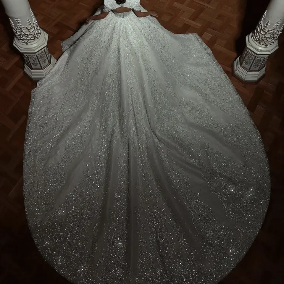 High-angle rear view of a sparkling sequin bridal ball gown showcasing a dramatic sweeping court train heavily scattered with micro-glitter.