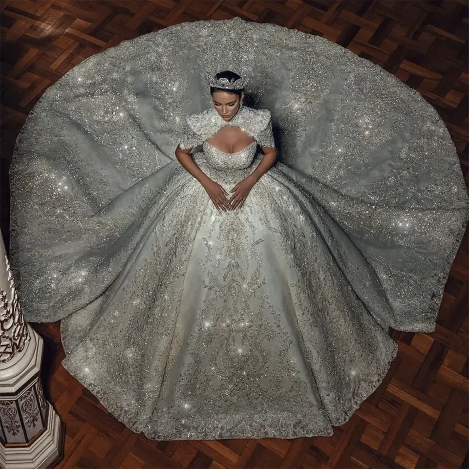 Royal princess style wedding dress with all-over sequin embroidery and a voluminous full tulle skirt layout, paired with a matching crystal bridal tiara crown.