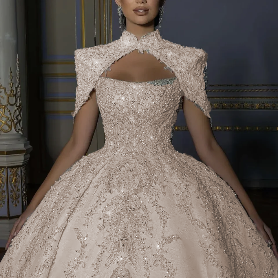 Elegant warm champagne toned backless bridal ball gown with a high-collar embroidered capelet jacket, designed for a modern fairy tale royal wedding.