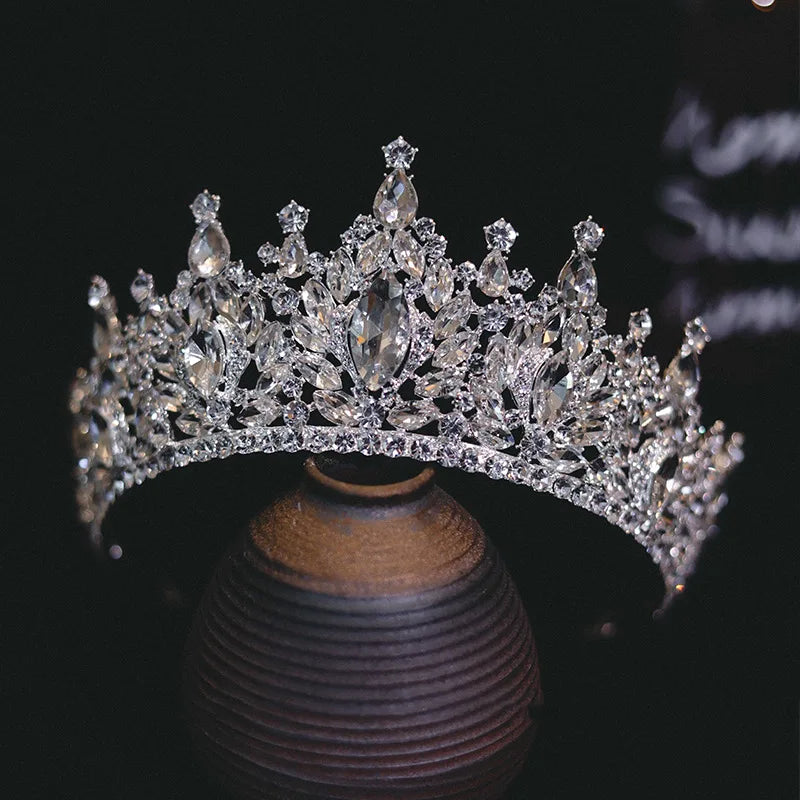 Elegant silver rhinestone bridal tiara crown positioned atop a dark vintage ceramic vase.