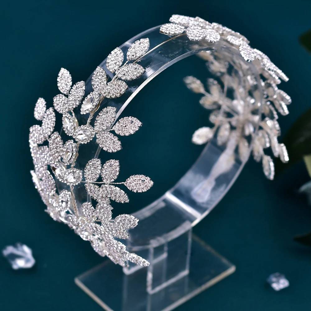 Side-profile view of a sparkling crystal leaf bridal tiara on a clear acrylic mannequin display