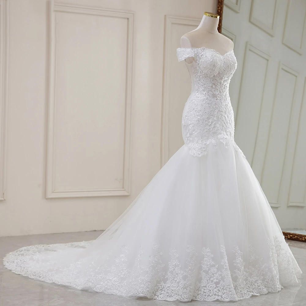 Side profile of an elegant mermaid-style wedding dress, showcasing the off-the-shoulder neckline and sophisticated embroidery.