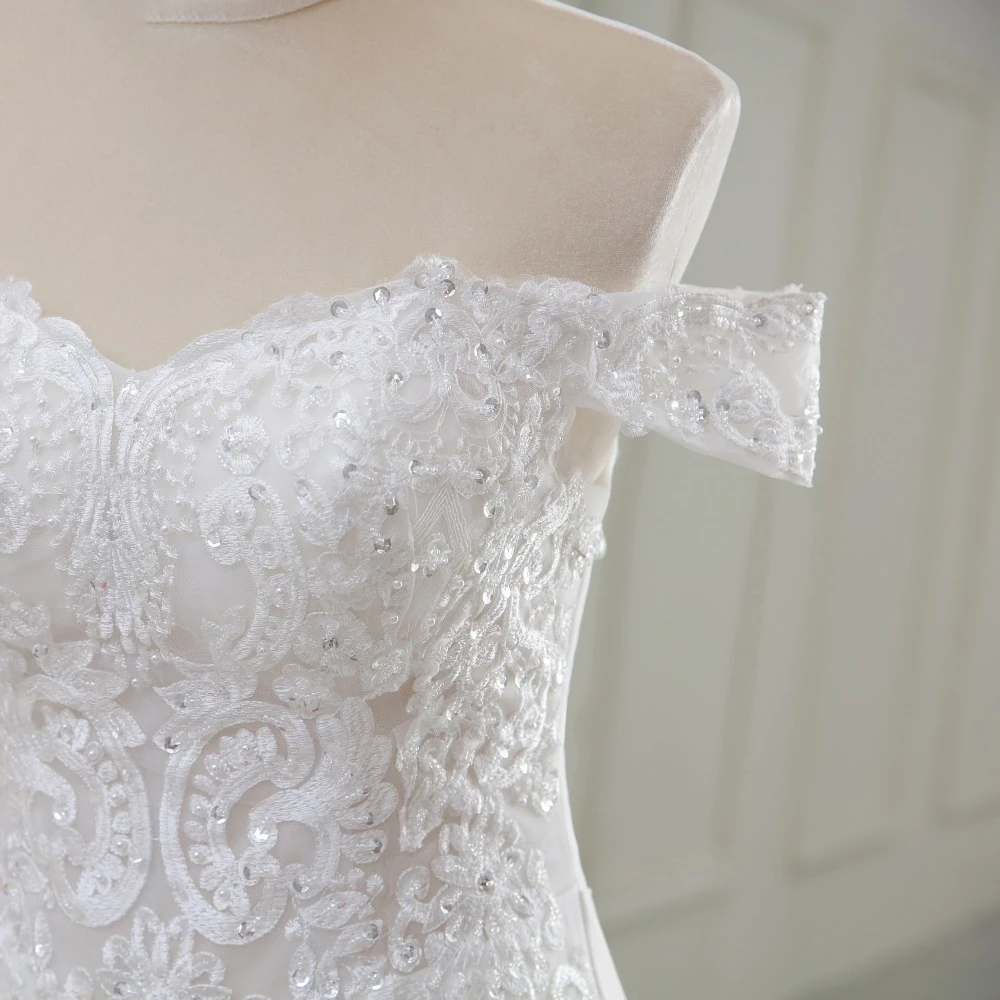 Close-up detail of the intricate beaded floral lace and delicate off-the-shoulder sleeves on the luxury bridal gown.