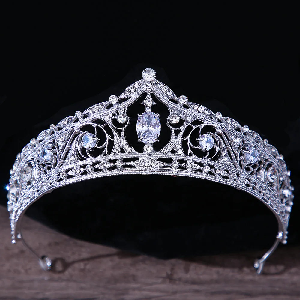 A classic silver crystal bridal tiara featuring a prominent oval-cut center gemstone nestled within intricate rhinestone scrollwork.