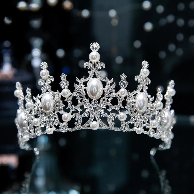 An ornate silver wedding headpiece heavily embellished with round and oval white pearls and sparkling rhinestone clusters.