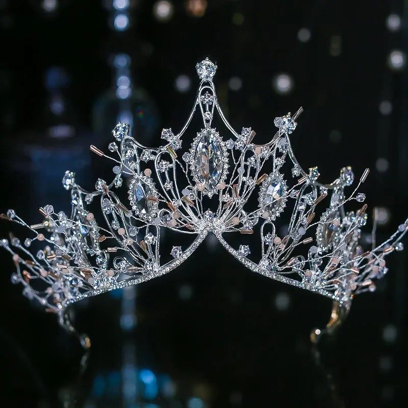 A unique, branch-style pageant headpiece featuring wire-wrapped crystals, marquise rhinestones, and subtle blush pink bead accents.