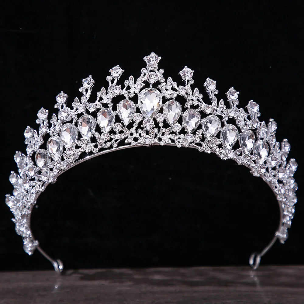 A classic bridal diadem crown boasting a symmetric layout of large pear-shaped crystals and delicate rhinestone vines against a black background.