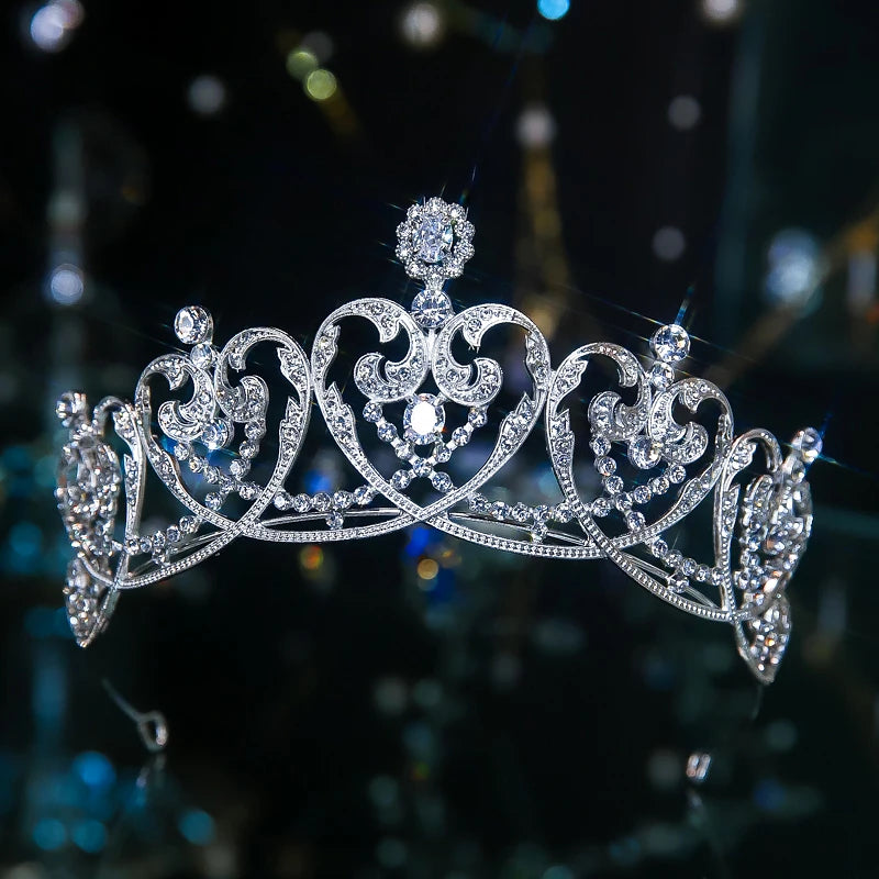 An elegant silver pageant headband tiara with symmetric heart-shaped scrollwork and a central crystal accent.