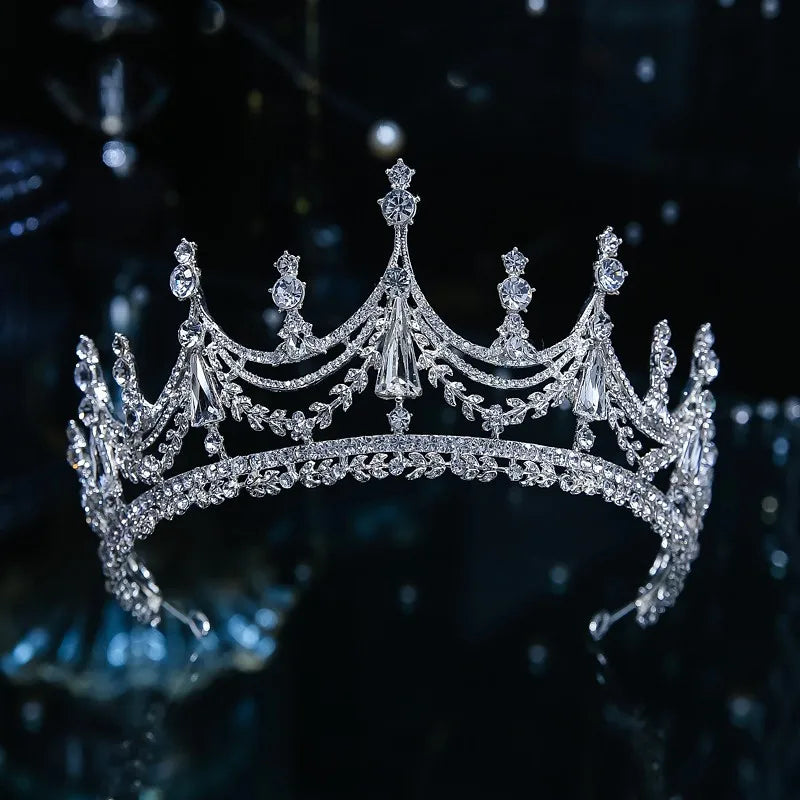 Front view of a majestic silver wedding crown featuring high arches, drop crystal accents, and delicate leaf branch filigree.