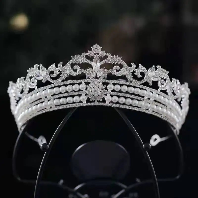 A three-tiered silver wedding headpiece featuring rows of white pearls anchored by a central crystal flower burst emblem.