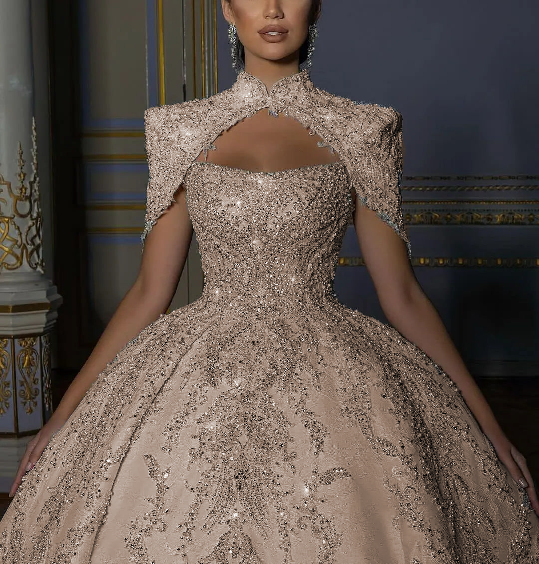 Elegant warm champagne toned backless bridal ball gown with a high-collar embroidered capelet jacket, designed for a modern fairy tale royal wedding.