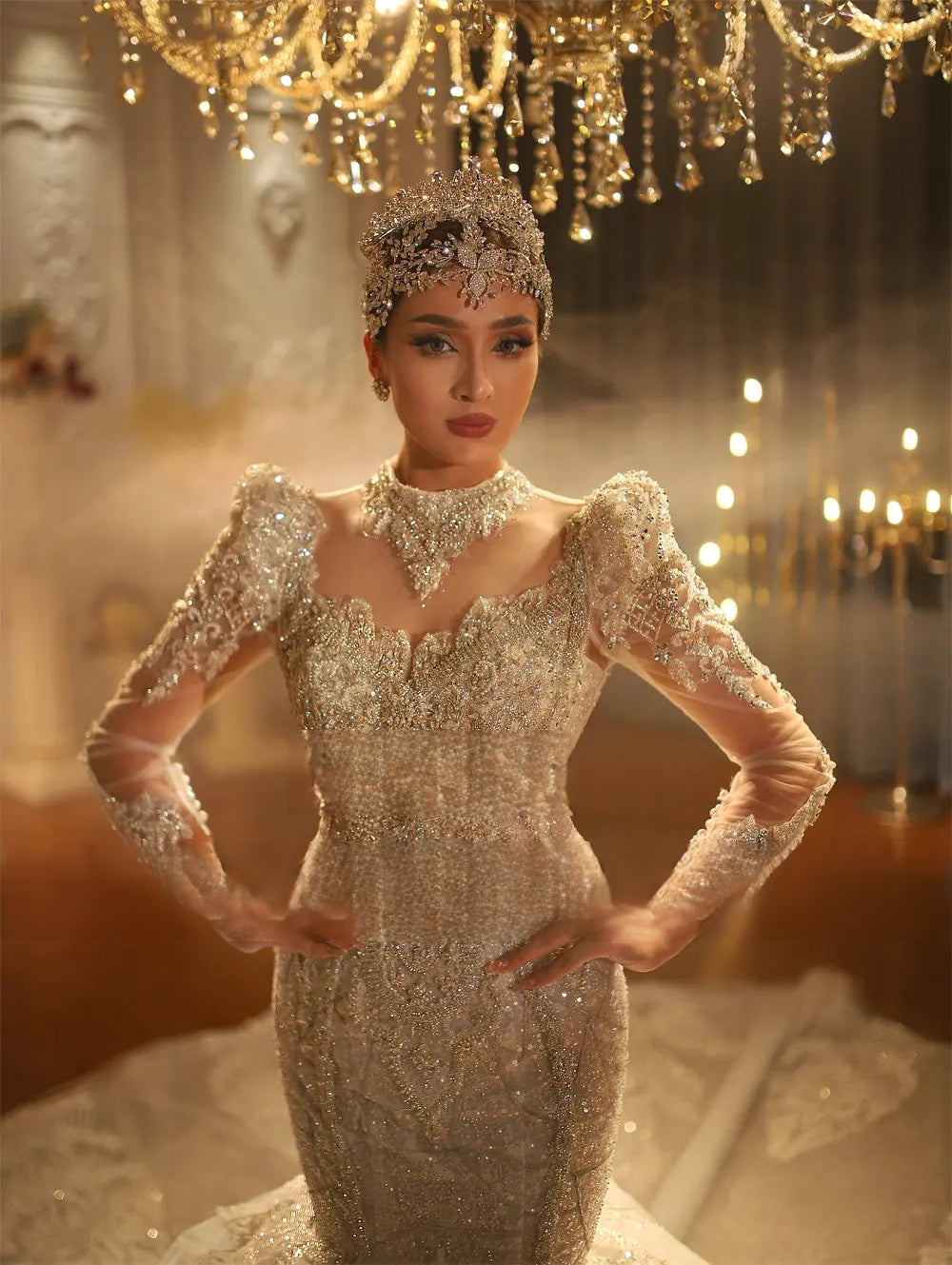 Close-up shot of a bride in a beaded mermaid gown showcasing an intricate crystal collar, transparent long sleeves, and an elaborate matching silver crown.