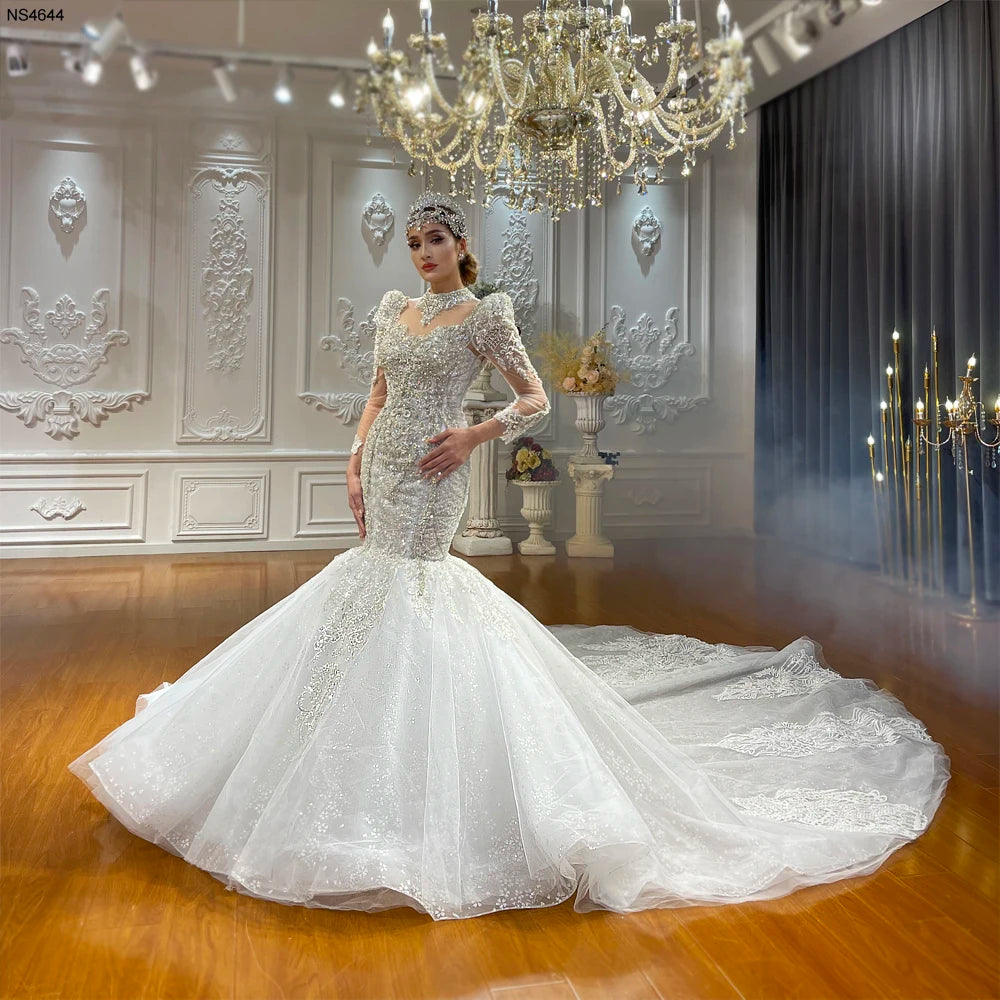 Side view of a fitted lace mermaid bridal gown with a massive, spreading cathedral-length train and intricate silver embroidery.
