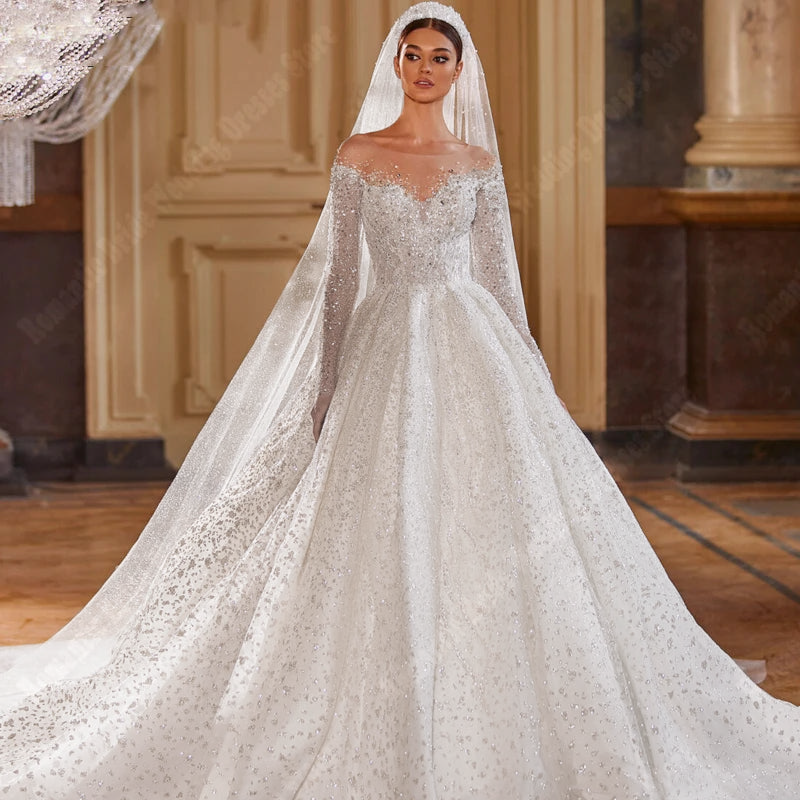 A detailed look at a bride wearing a bright sequin A-line wedding dress, featuring long sleeves, V-neck styling, and a matching veil.