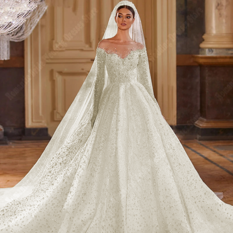 A formal shot of a bride in a luxury sequined A-line bridal gown, emphasizing the long-sleeve design and mopping-length hemline.