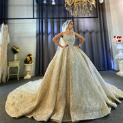 Full-length front view of an elegant model wearing a luxury vintage sleeveless wedding dress featuring a massive, sparkling champagne ball gown skirt and a long cathedral veil in a grand showroom.
