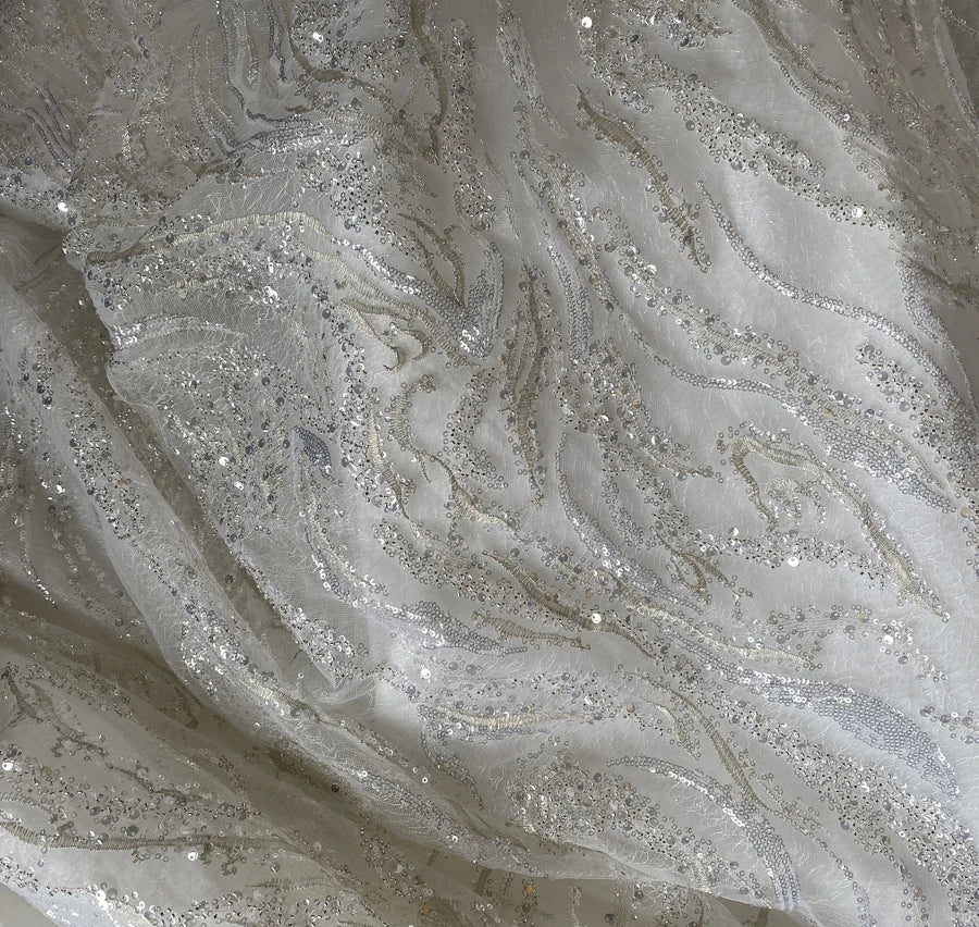 Close-up macro detail of the luxury vintage bridal gown fabric, showcasing the intricate, high-density silver and champagne sequin embroidery layered over delicate white lace.