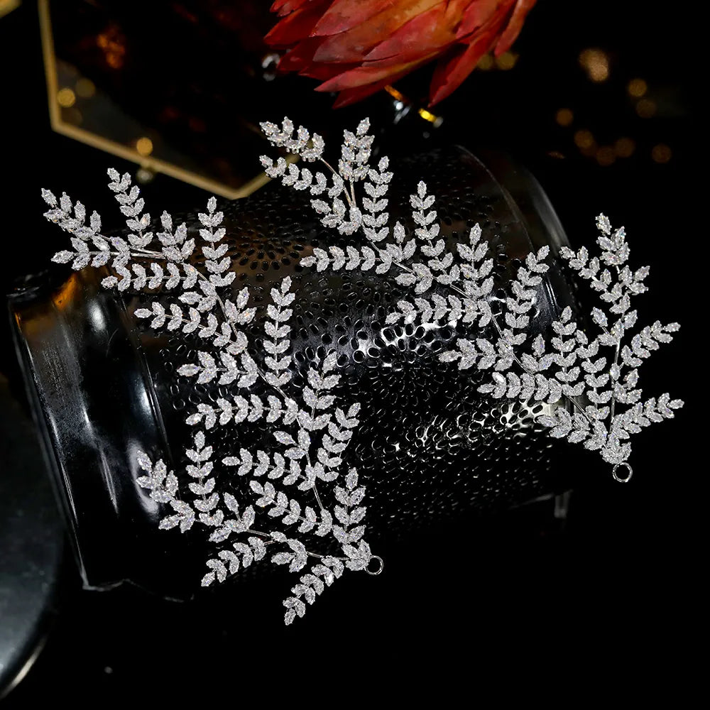 Luxury wedding hair accessories featuring a pair of silver bridal hairpins with a sparkling pave crystal leaf branch pattern wrapped around a dark base.