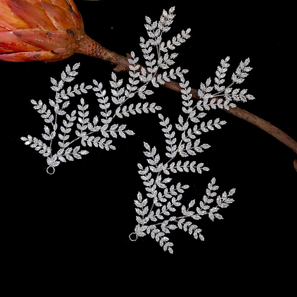 Handcrafted elegant wedding hair ornaments designed with clear marquise rhinestones in a detailed leaf branch setting, styled next to a reddish plant stem.