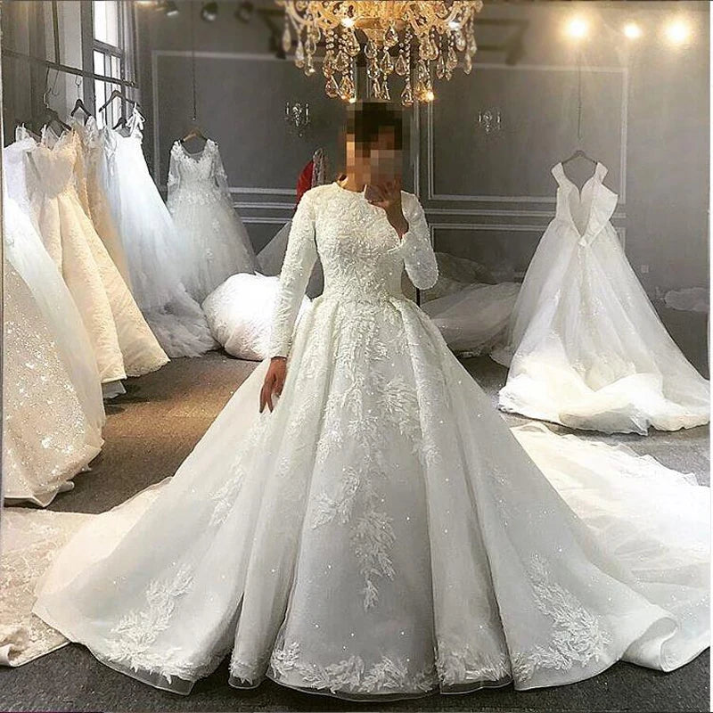 Elegant white Muslim wedding dress with a modest high neck and long sleeves, showcasing heavy crystal beading and a voluminous skirt with detailed lace trim at the hem.