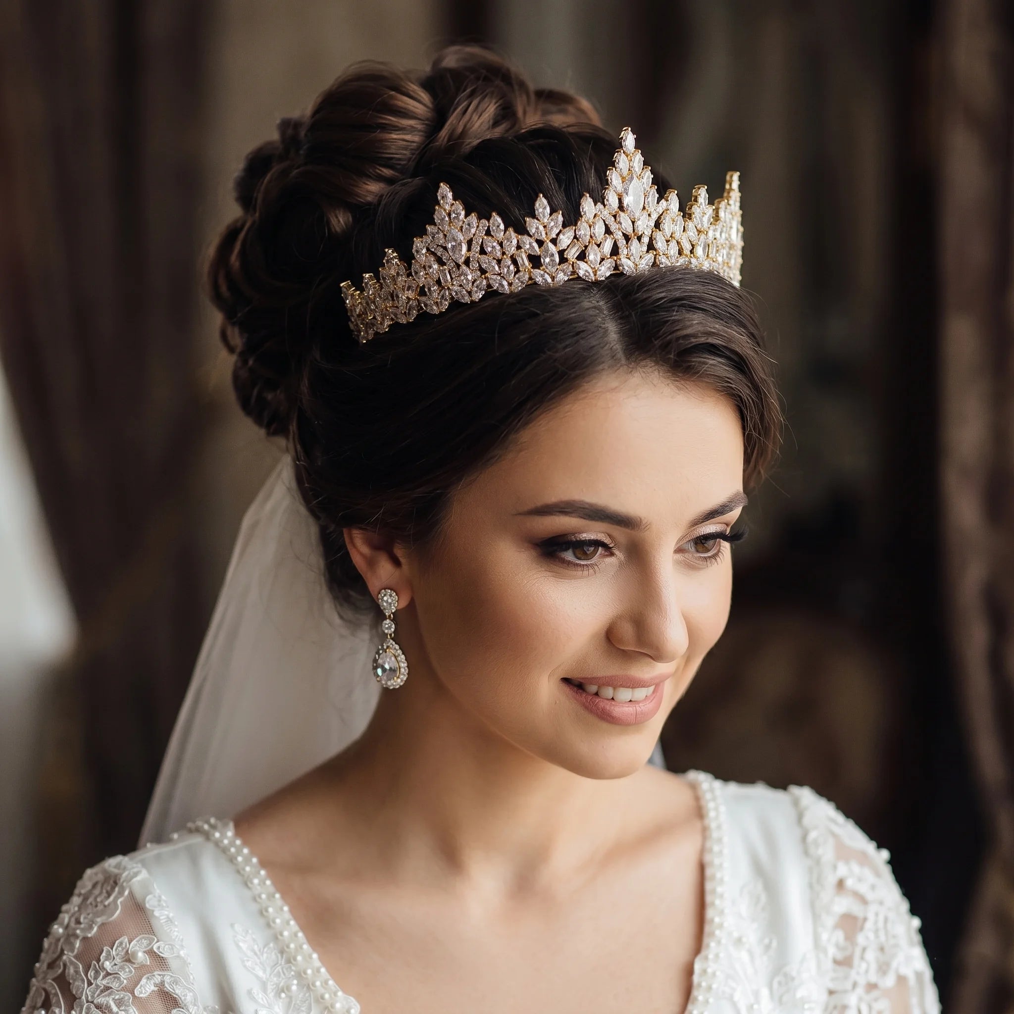 A smiling bride wearing a luxury gold zircon bridal tiara crown and matching drop earrings.