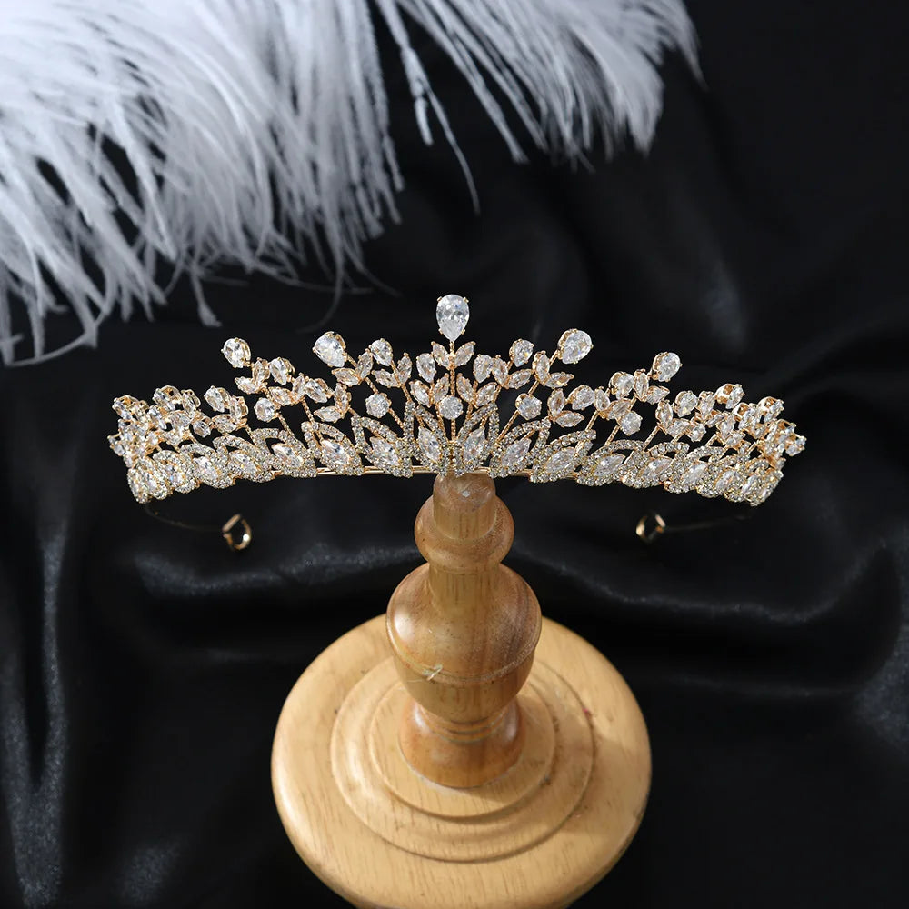 Elegant gold zircon bridal tiara headpiece displayed vertically on a wooden stand against a black background.