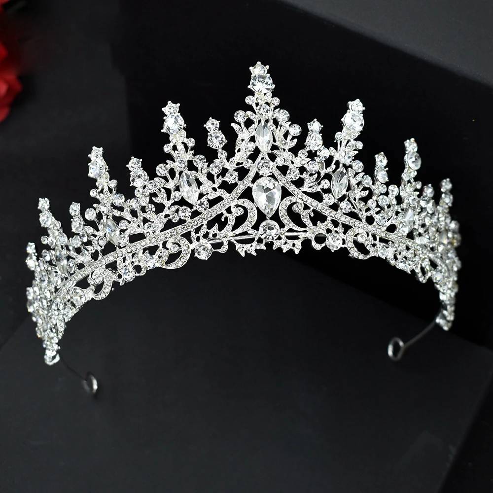 A regal silver pageant headpiece featuring a striking open-pattern filigree design and a brilliant crystal center teardrop gem.