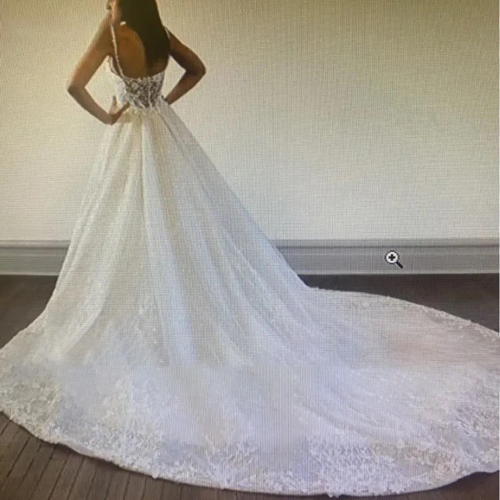 A rear view of a mermaid bridal gown showing a long, detachable tulle train, perfect for a grand wedding entrance.