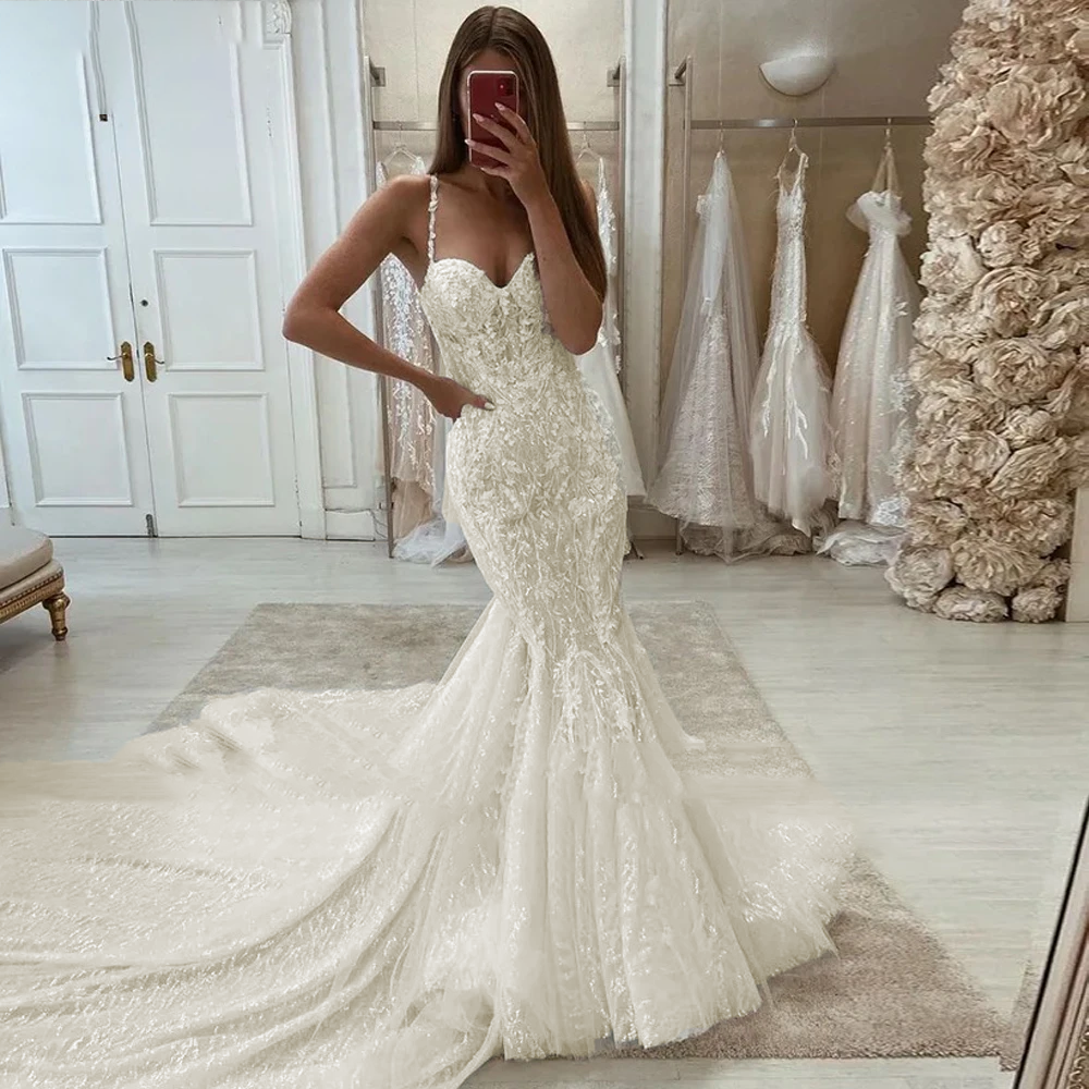 A bride posing in a glamorous mermaid wedding dress, highlighting the sparkling beaded lace appliques and figure-flattering mermaid silhouette.
