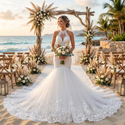 Smiling bride wearing a halter neck lace mermaid wedding dress with an embellished keyhole bodice and a dramatic flared tulle skirt under a coastal beach wedding arch.