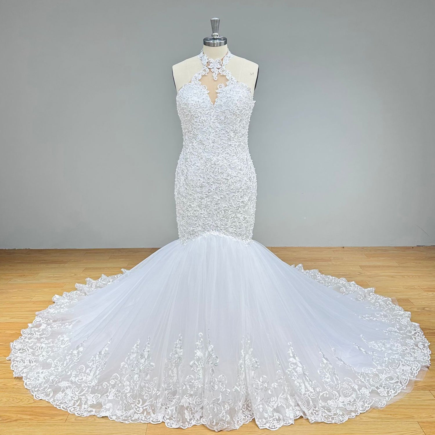 Front display of a vintage-inspired beaded halter neck trumpet wedding dress highlighting the form-fitting silhouette and scalloped lace details on a dress form.