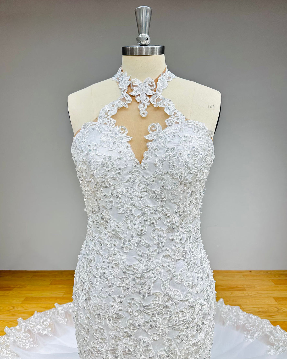 Detailed front view of a halter style wedding dress neckline featuring a geometric keyhole cutout design embellished with glistening rhinestones and sequins.