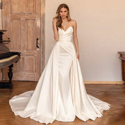 A bride wearing an elegant satin mermaid wedding dress with a detachable train, featuring a chic sweetheart neckline and a sophisticated silhouette.