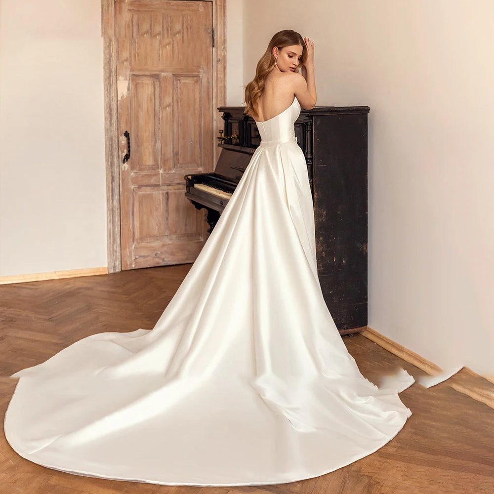 A back view of a bride in a mermaid satin wedding gown, highlighting the long, elegant train and clean, simple aesthetic.