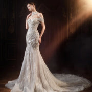 Model wearing a luxury crystal and pearl beaded mermaid wedding dress with an off-the-shoulder sweetheart neckline, a sweeping train, and a matching high-neck statement choker.