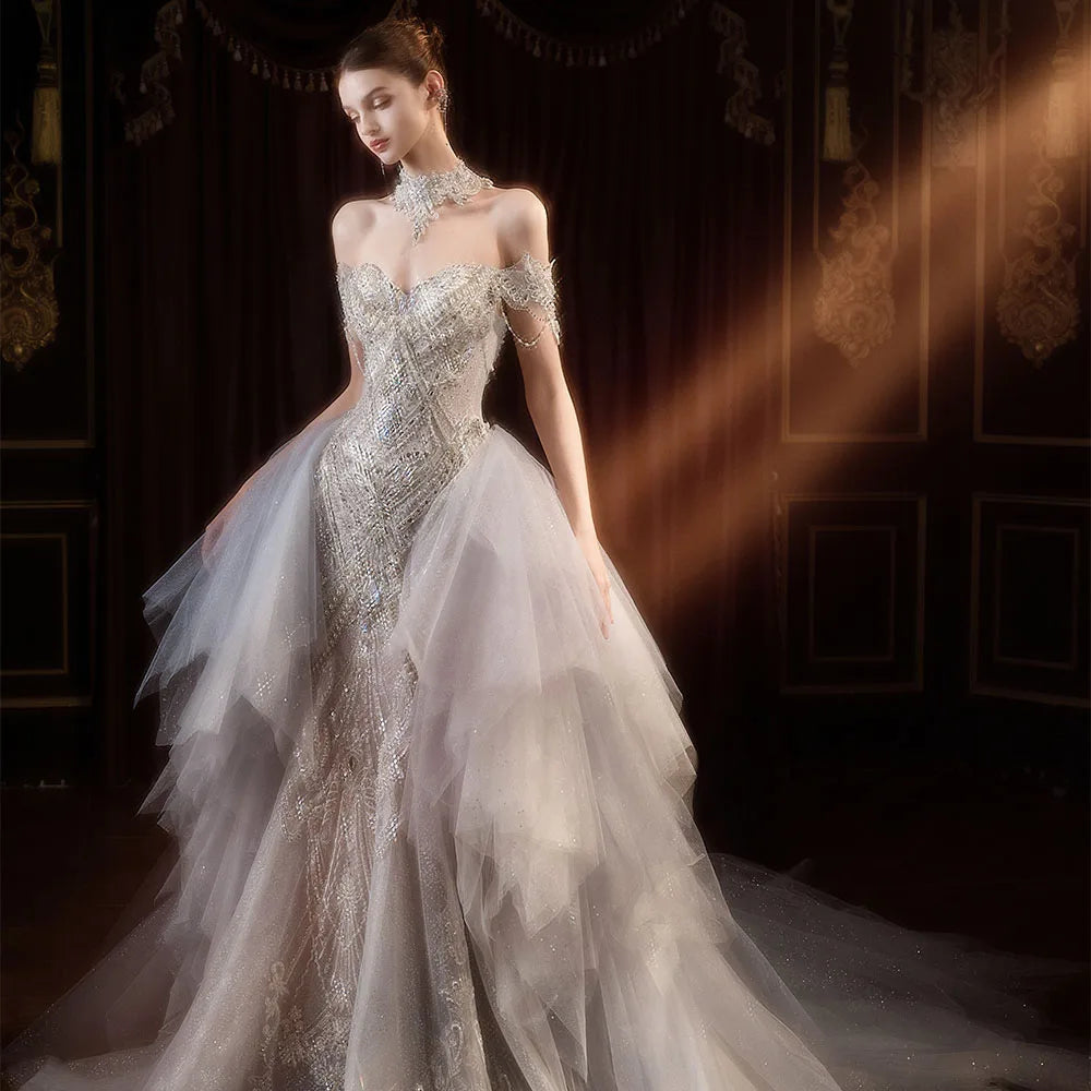 Elegant front view of a shimmering silver-beaded mermaid wedding dress showcasing a detachable layered tulle overskirt and a high-neck crystal collar.