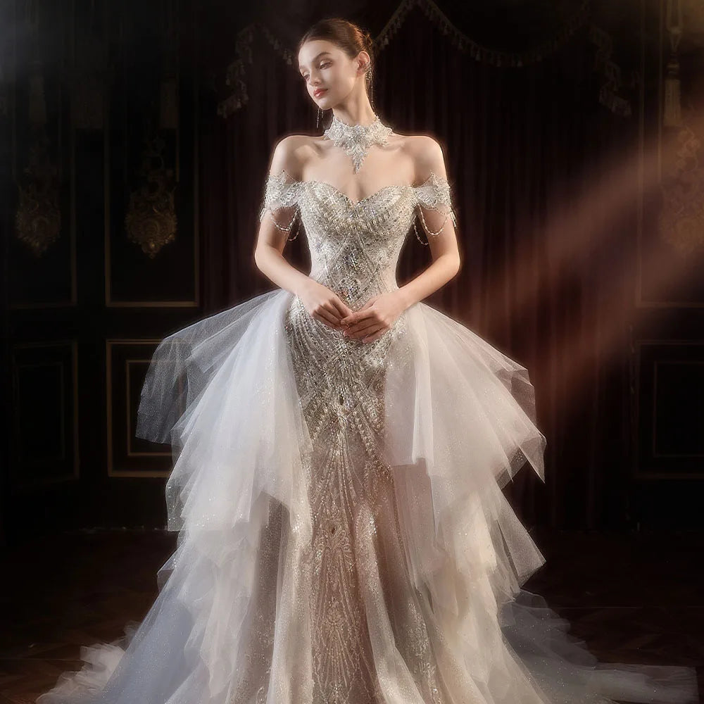 Full-length front view of a glamorous beaded mermaid wedding gown with an attached cascading tulle overskirt framing a heavily embellished geometric pearl bodice.