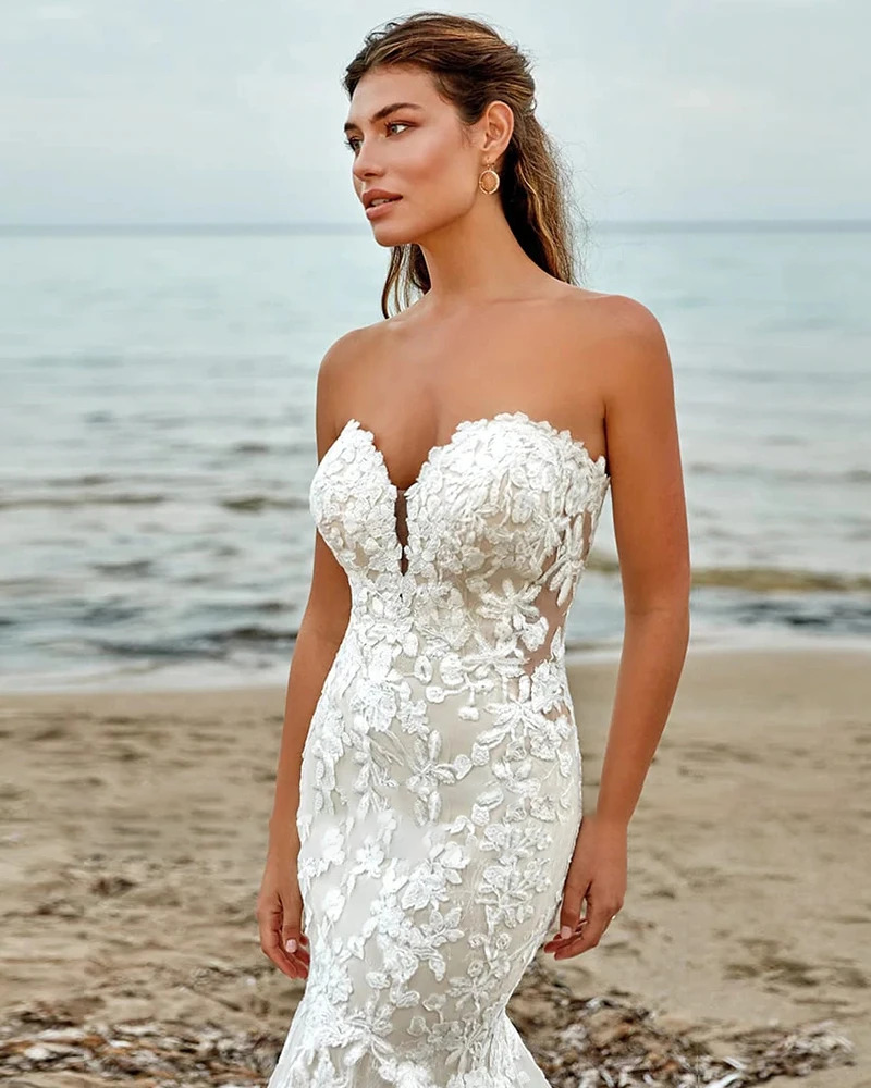 Glamorous mermaid wedding dress with an off-the-shoulder sweetheart neckline, fitted bodice covered in delicate floral lace appliques, and a multi-layered tulle court train.
