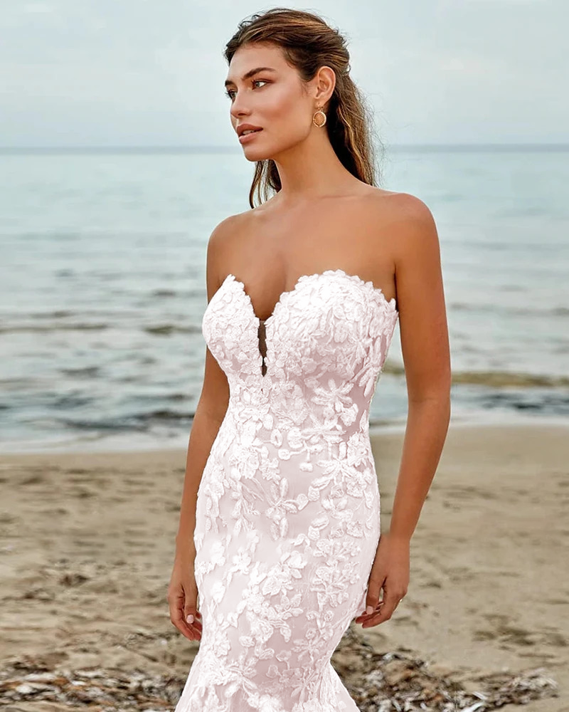 Romantic soft blush pink mermaid wedding dress with a contrasting white floral lace overlay bodice and elegant off-the-shoulder portrait cuffs.