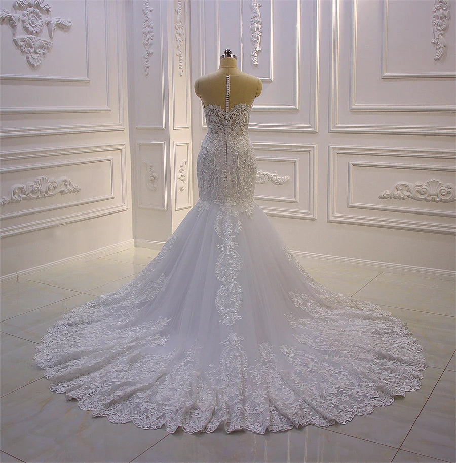 Rear view of the mermaid wedding dress without the cape, displaying an elegant row of covered buttons down the back and a wide circular lace-trimmed train.