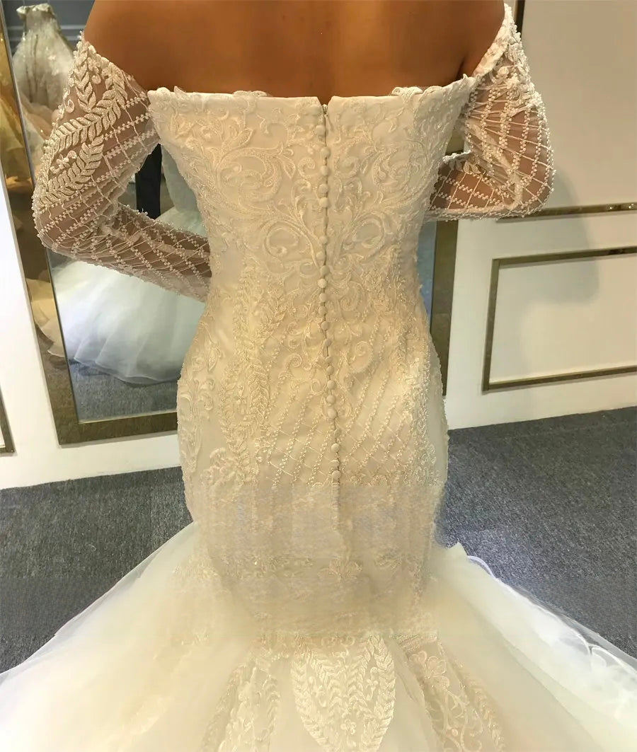 Rear view of the mermaid wedding dress bodice showcasing a line of covered buttons and elegant off-the-shoulder long lace sleeves.