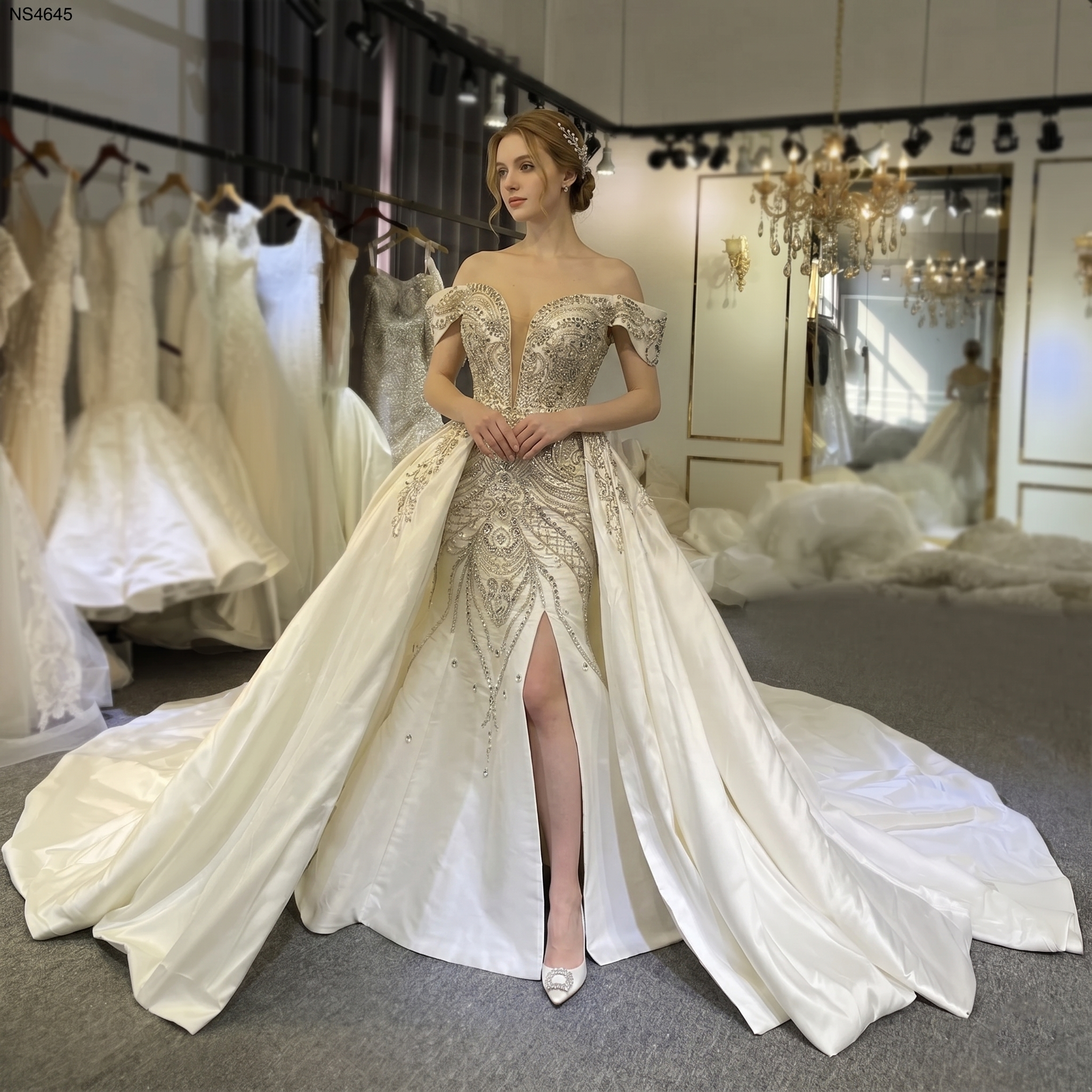 Elegant model wearing a Mikado satin mermaid wedding dress featuring an intricate beaded bodice, off-the-shoulder straps, a high front slit, and a dramatic detachable ball gown train.