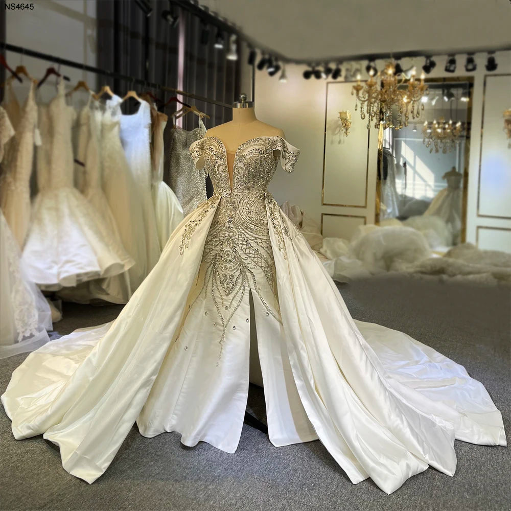 Front view of a sleeveless Mikado satin bridal gown on a mannequin, showcasing the heavily beaded bodice and mermaid silhouette with a detachable satin ball gown overskirt.