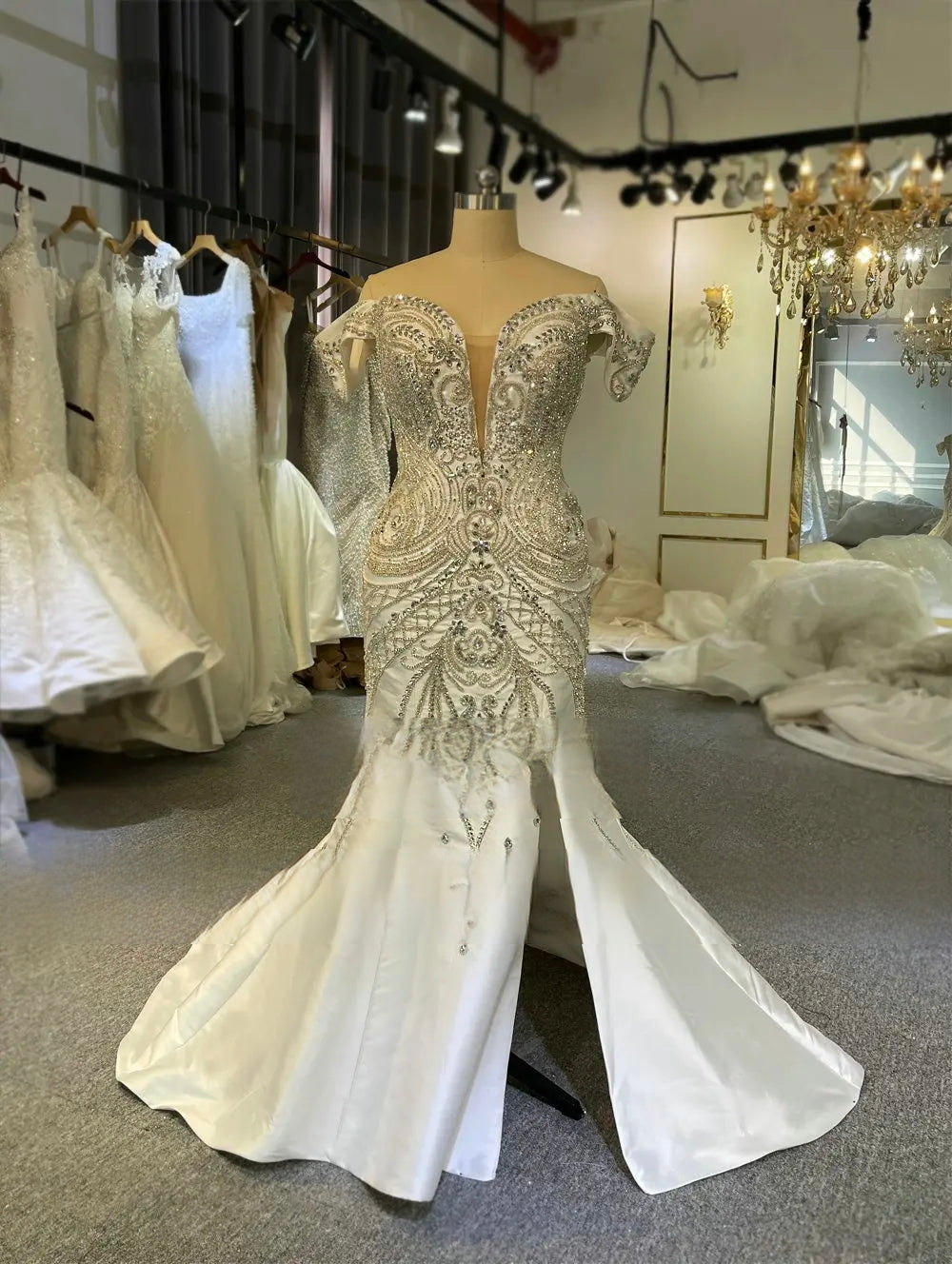 Mermaid style Mikado satin wedding dress on a mannequin, highlighting the ornate silver crystal beading, plunging illusion neckline, and daring high front slit.
