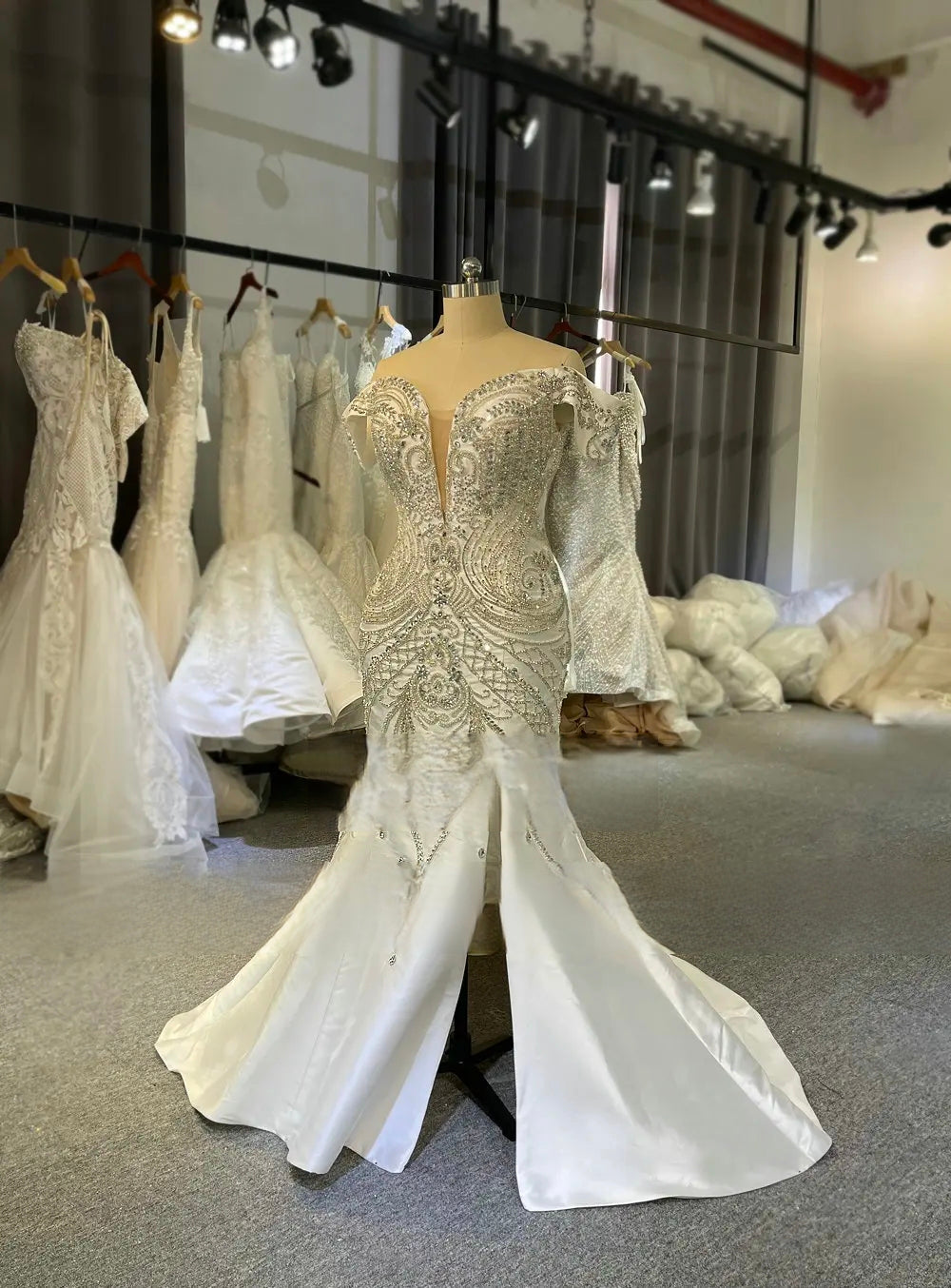 Luxury Mikado satin sleeveless wedding dress with a trumpet silhouette and a high slit, adorned with exquisite beaded appliques in a professional bridal showroom.