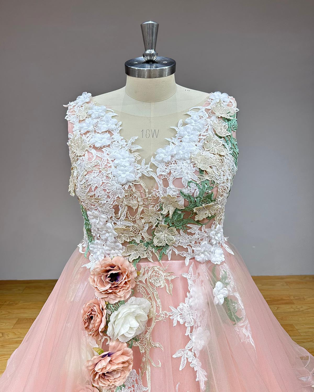 Detailed front view of a sleeveless sweetheart bridal bodice under a sheer illusion high-neck overlay, embellished with intricate white and green botanical lace appliques and pastel 3D silk roses.