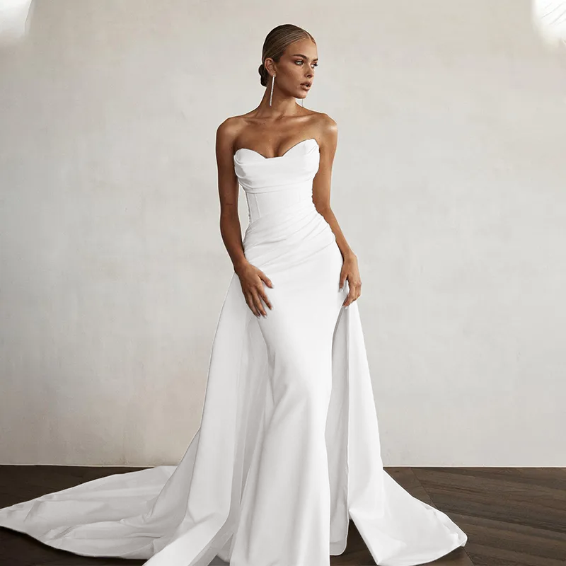 Full view of a sleek modern mermaid wedding dress with a sweetheart neckline, showcasing the elegant train and side-slit detail.