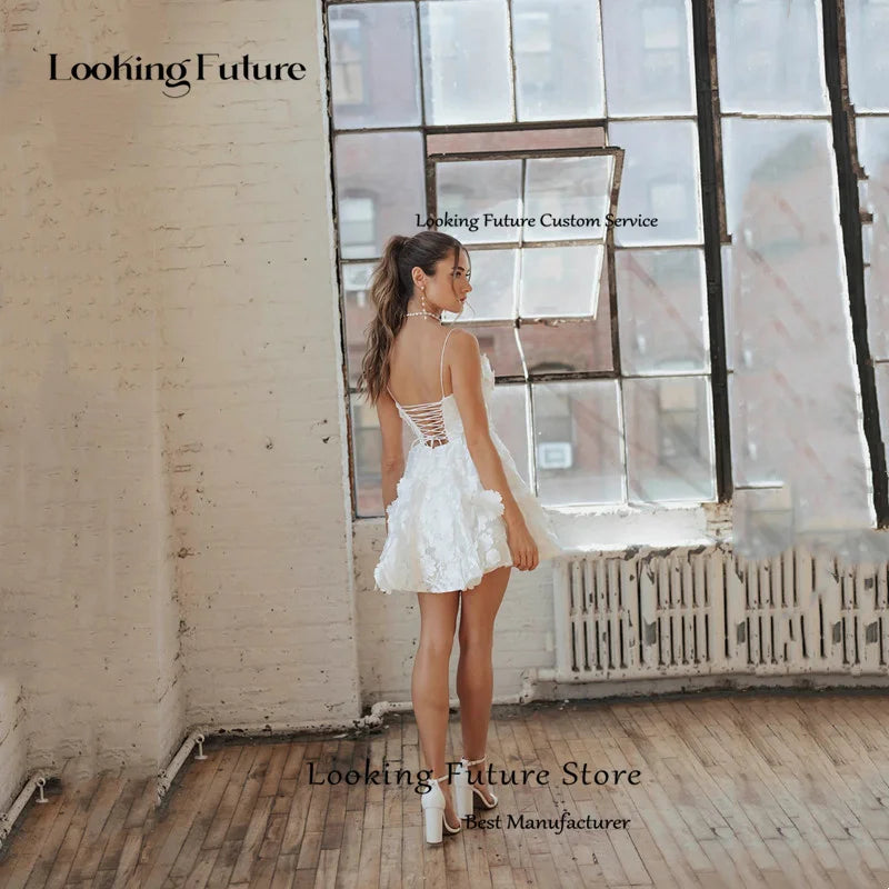 Rear profile view of a short backless bridal mini dress showcasing a delicate criss-cross lace-up corset back design and a structured 3D floral applique tulle skirt.