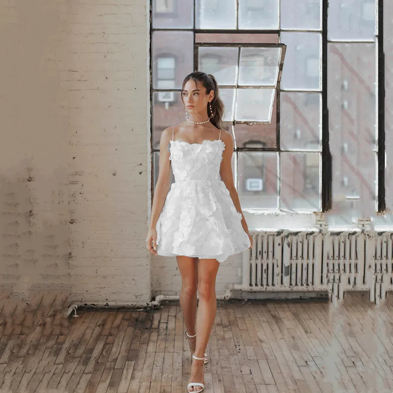 Stately mini A-line bridal gown with all-over dimensional 3D flower appliques and dainty spaghetti straps, ideal for a bachelorette party or bridal shower look.