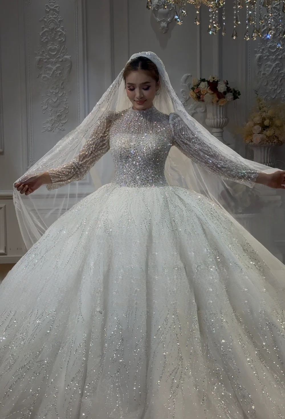 Front perspective of an elegant model wearing a full-length, long-sleeved modest Muslim wedding dress, demonstrating the intricate beading, high neckline, and matching sparkling veil.